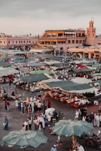 La plaza Jemaa el-Fnaa en Marrakech llena de gente, puestos y artistas callejeros al atardecer