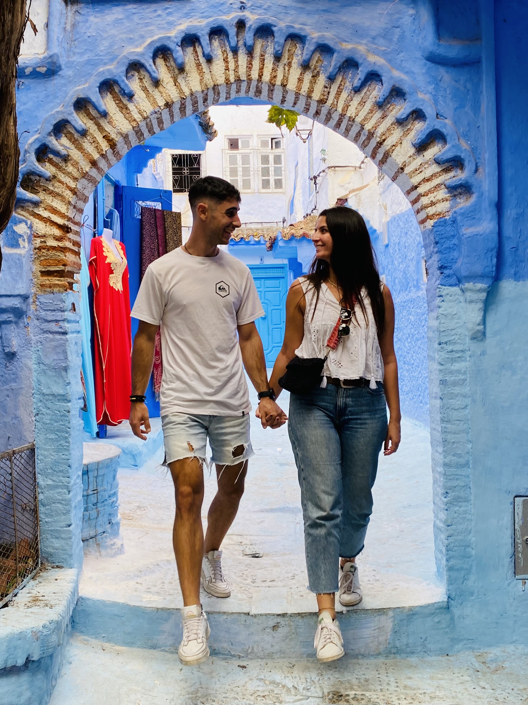 Pareja de viajeros paseando por un arco azul de la medina de Chefchaouen