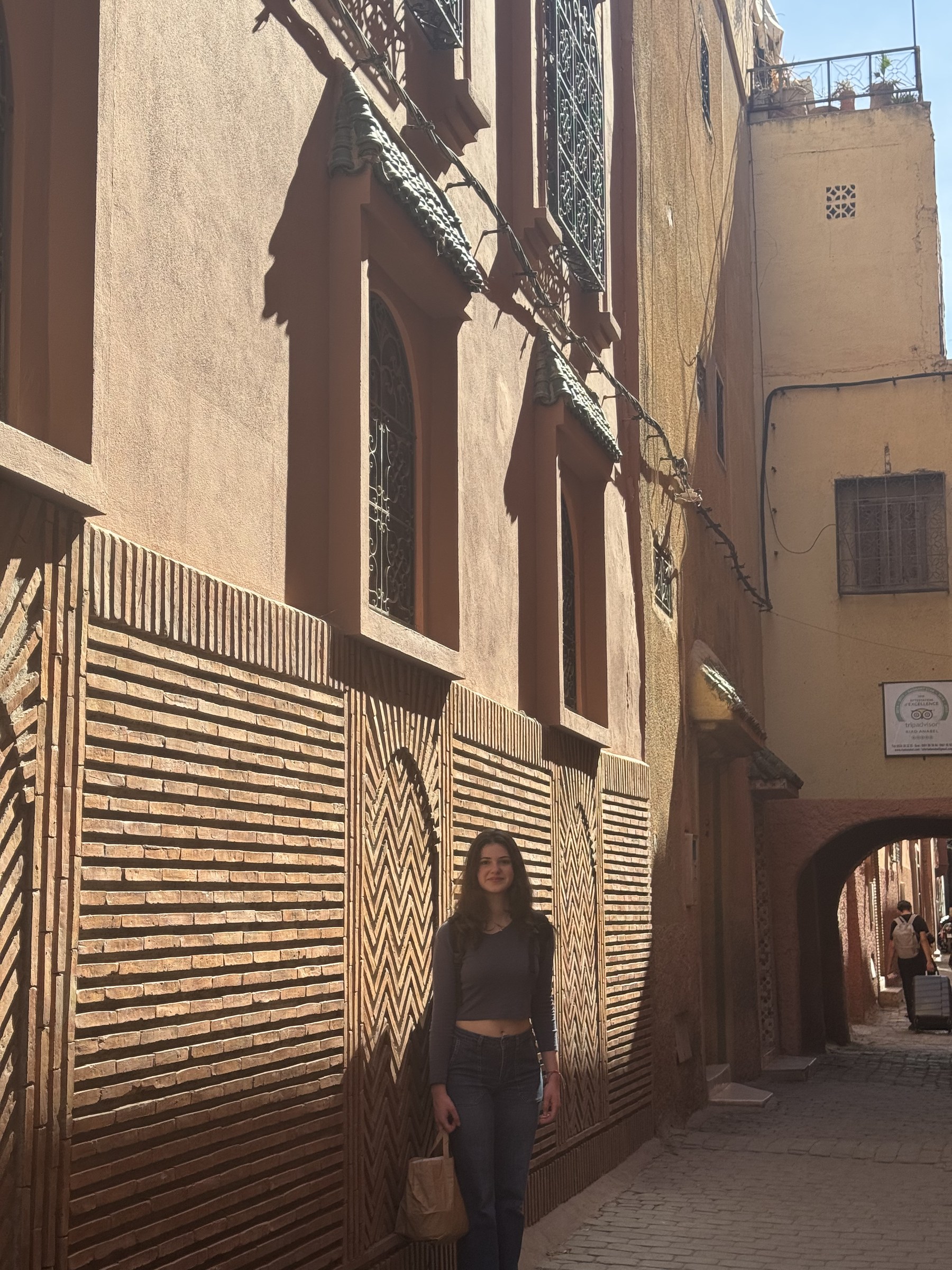 Viajera en callejón de la medina de Marrakech con pared de ladrillos en patrón geométrico