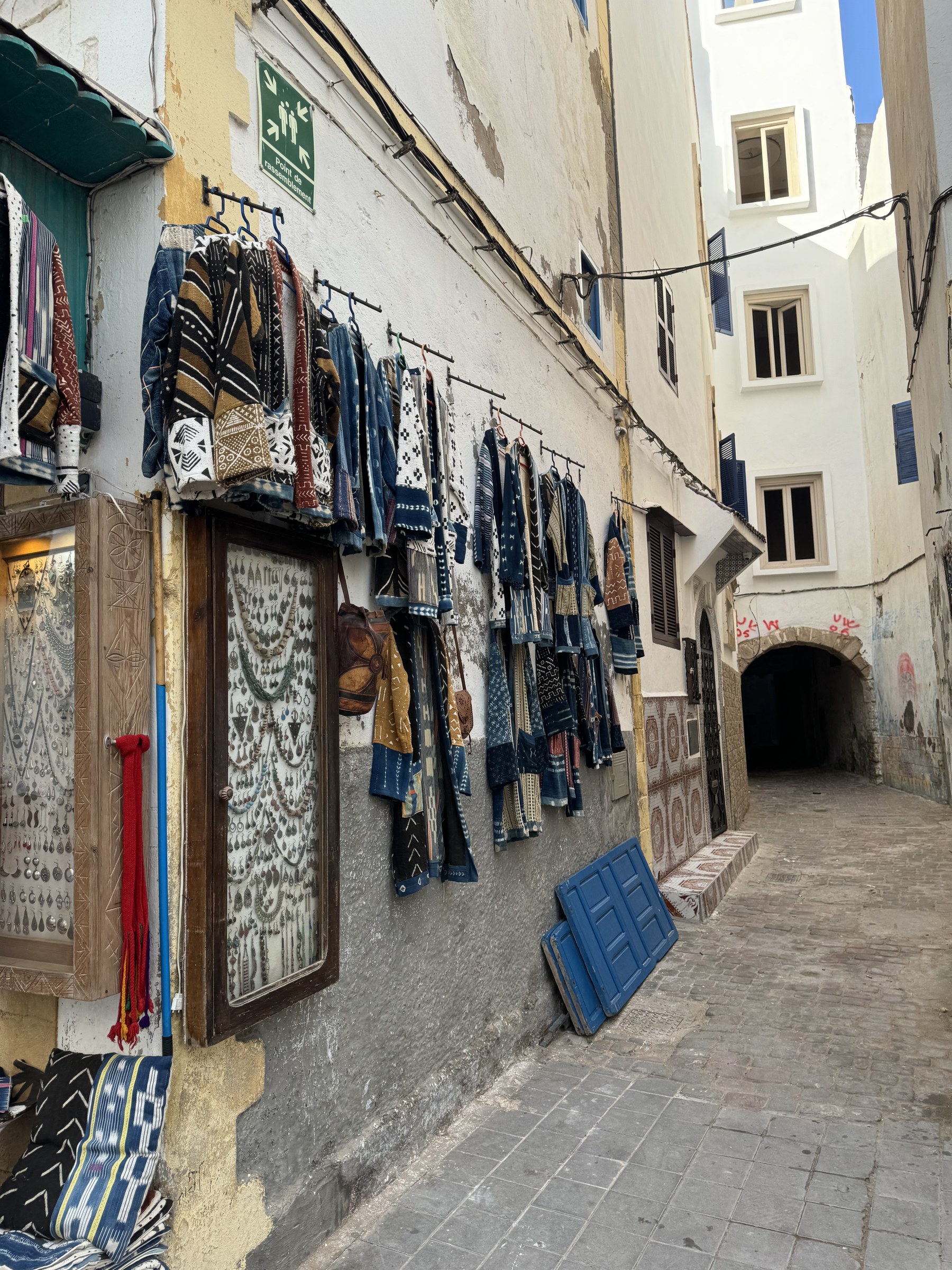 Callejón de la medina de Tánger con ropa artesanal y textiles bereberes colgados en la fachada