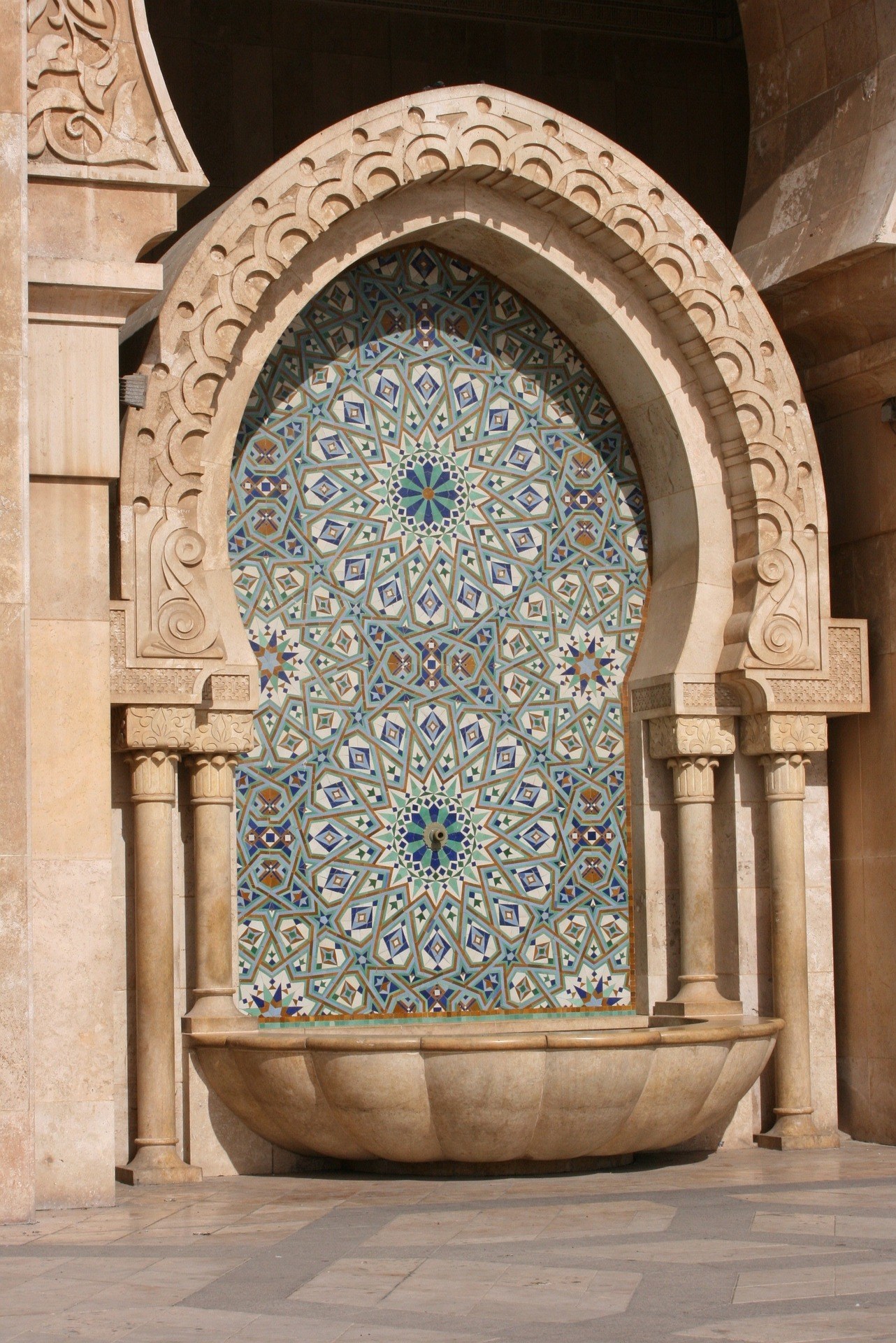 Fuente de mármol con mosaico de zellige azul y verde en la Mezquita Hassan II de Casablanca