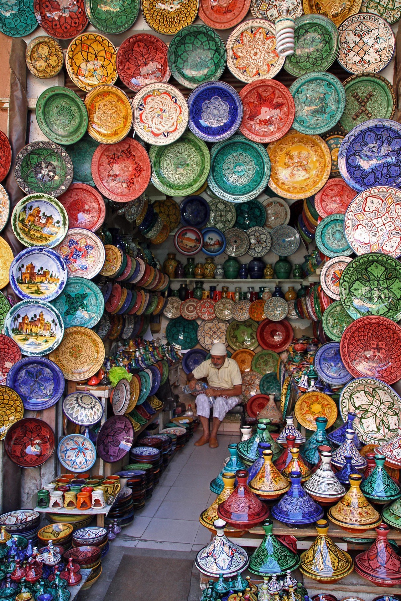Puesto de cer&aacute;mica marroqu&iacute; en el zoco de Marrakech con platos pintados y tajines de colores