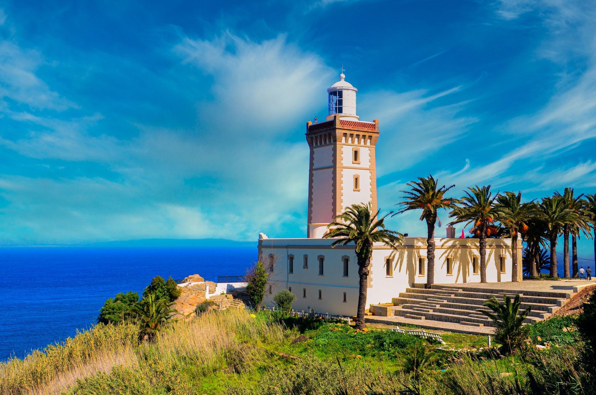 Faro de Cabo Espartel en Tánger, Marruecos, con palmeras y el estrecho de Gibraltar al fondo